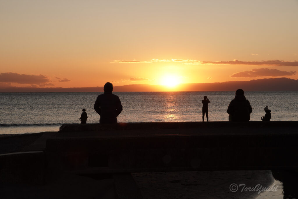 海の夕日を見る人たち